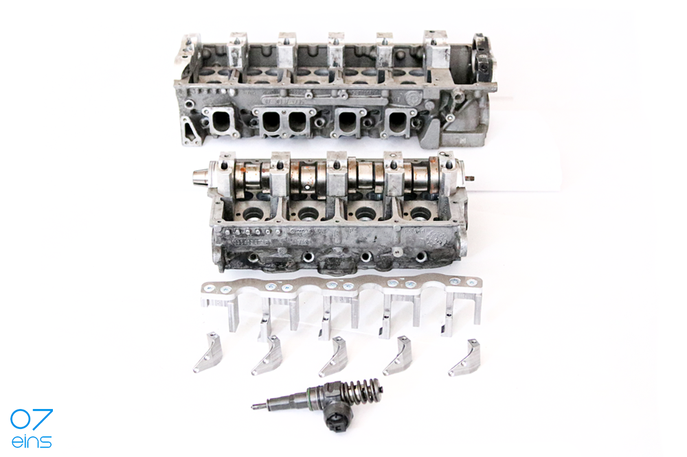Geöffneter TDI-Zylinderkopf mit demontierten Pumpe-Düse-elemente und der original PDE-Brücke in Einzelteilen
